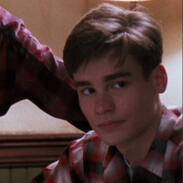 a picture of neil perry from dead poets society; a young man with short brown hair looking to the right